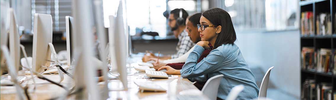 group of graduate degree students working on computers in the library at campus