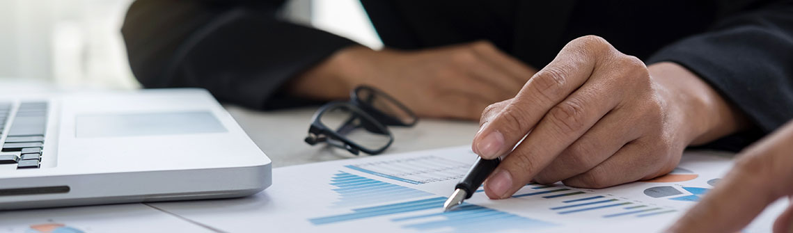 Photo of hands of an accountant doing calculations with document graph, digital tablet and laptop computer